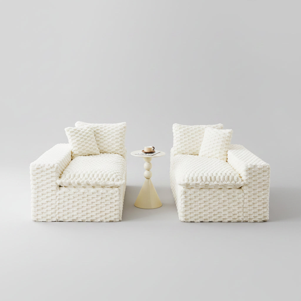 Two white textured armchairs in a living room setting with a small table and decor items.